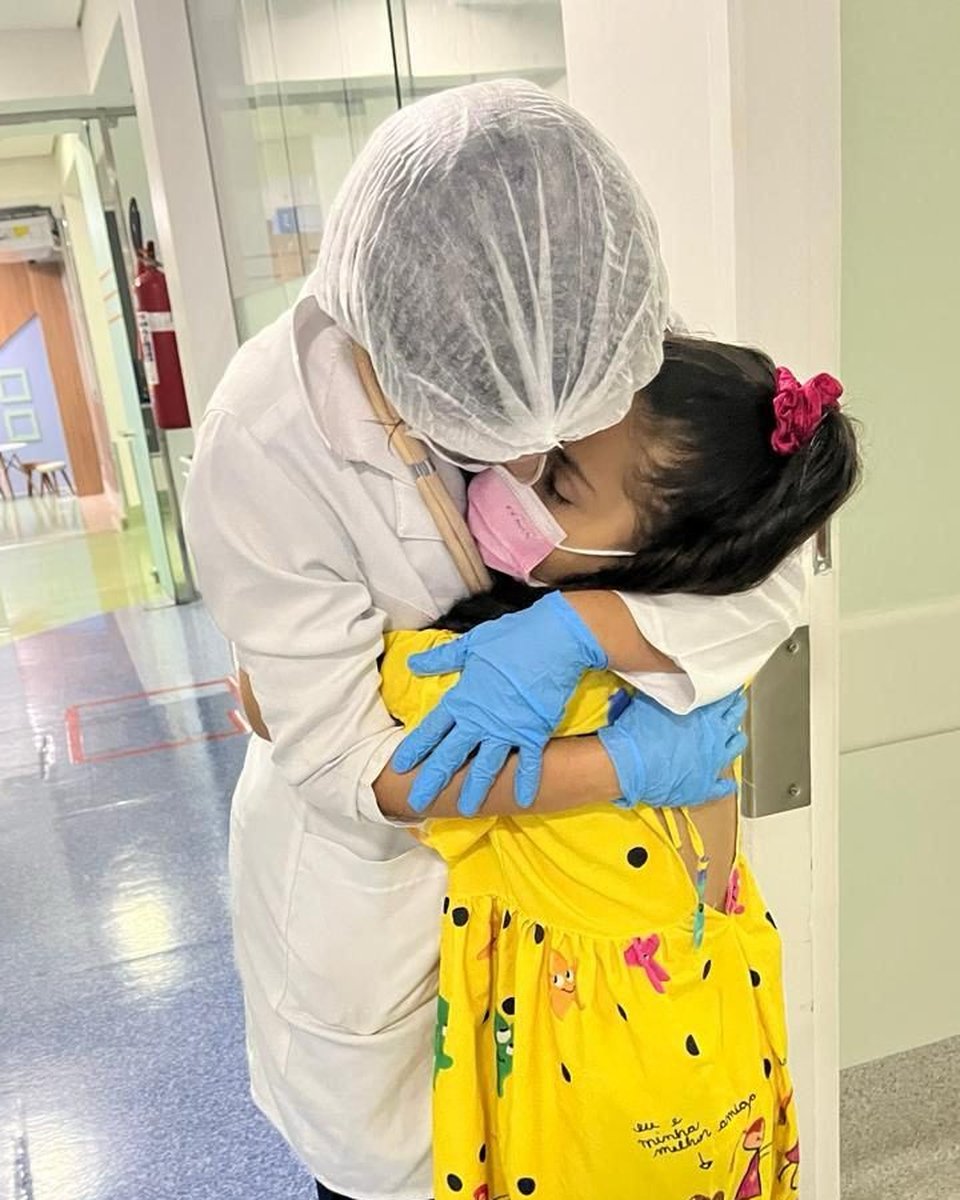 Profissional da Cuidare abraçando uma criança no hospital, em momento de alta